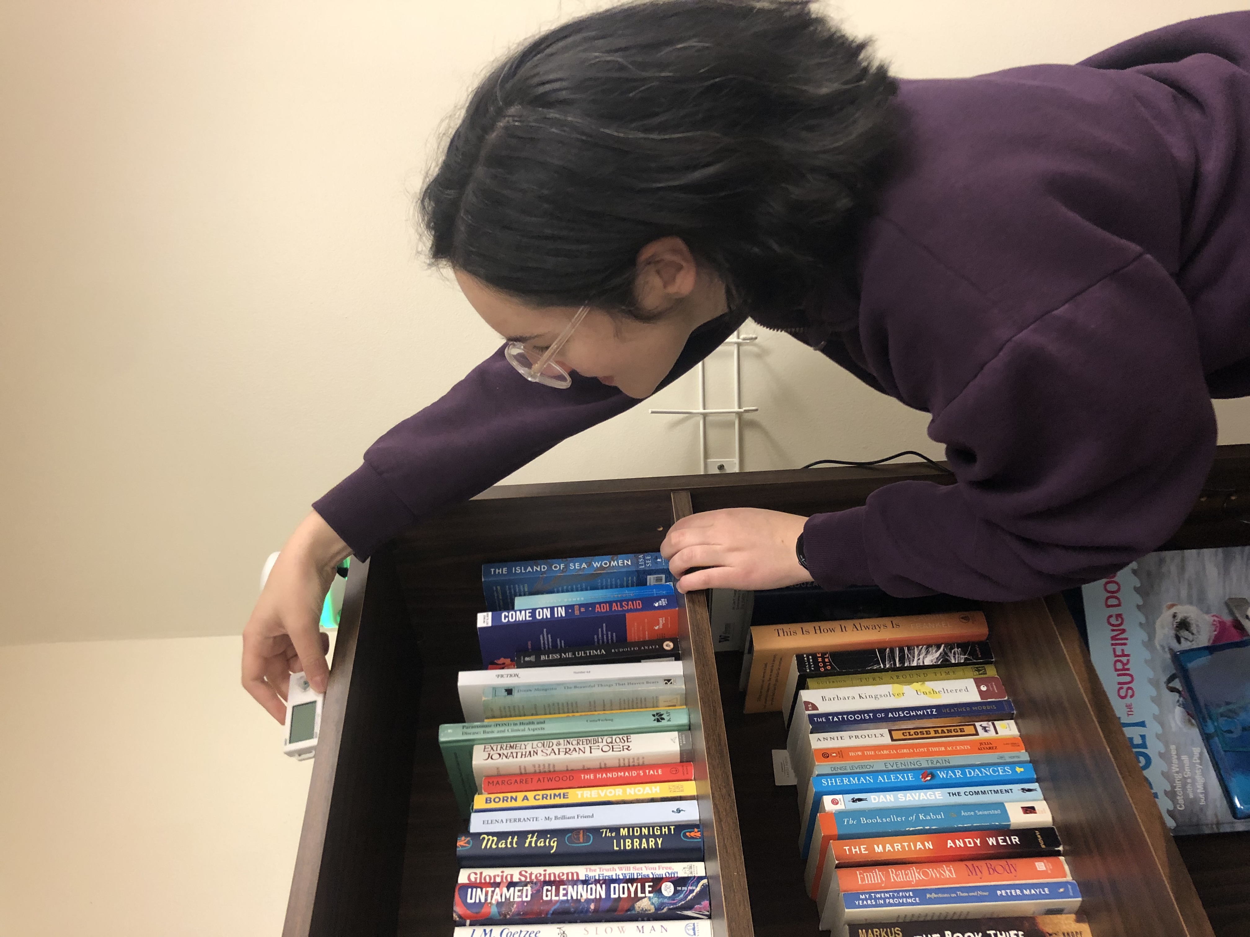 Martindale with her back to the camera reaches up to place a small air quality sensor on top of a bookshelf.