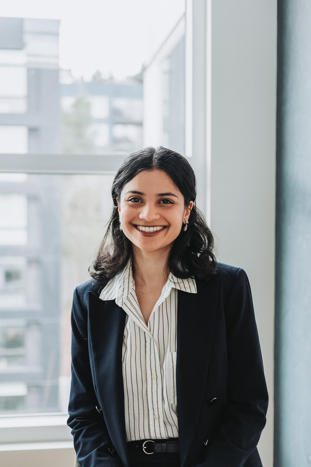 Headshot of Aesha Mokashi standing inside in front of a window.